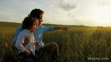 幸福的<strong>家庭</strong>，父亲和儿子坐在绿色的麦田。父亲手指上美丽的日落。关闭